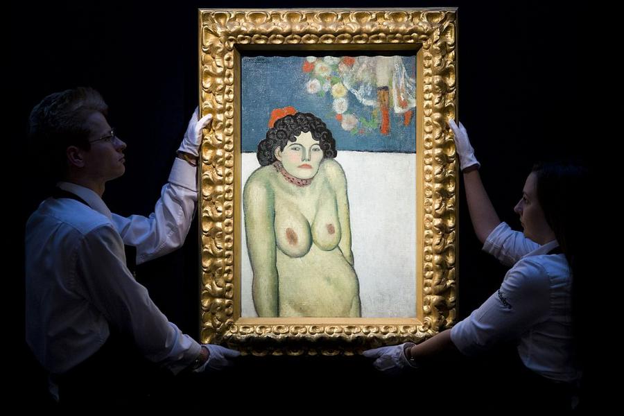 Employees of Sotheby's auction house pose for photographers with the 1901 painting 'La Gommeuse' by Spanish artist Pablo Picasso, estimated to sell for 60 million USD (53 million euro, 39 million GBP) at auction in New York, during a press preview in London on October 9, 2015 . AFP PHOTO / JUSTIN TALLIS -- RESTRICTED TO EDITORIAL USE, MANDATORY MENTION OF THE ARTIST UPON PUBLICATION, TO ILLUSTRATE THE EVENT AS SPECIFIED IN THE CAPTION (Photo credit should read JUSTIN TALLIS/AFP/Getty Images)