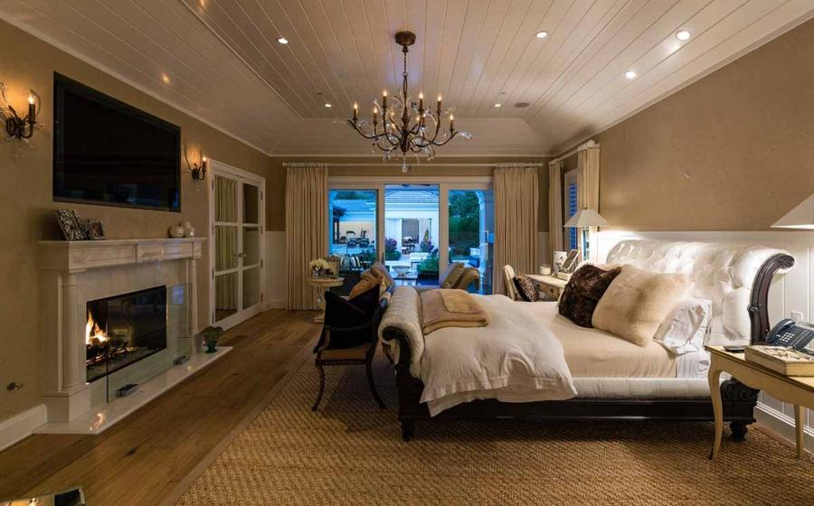 this-master-bedroom-features-a-massive-sleigh-bed-and-pale-wood-floors