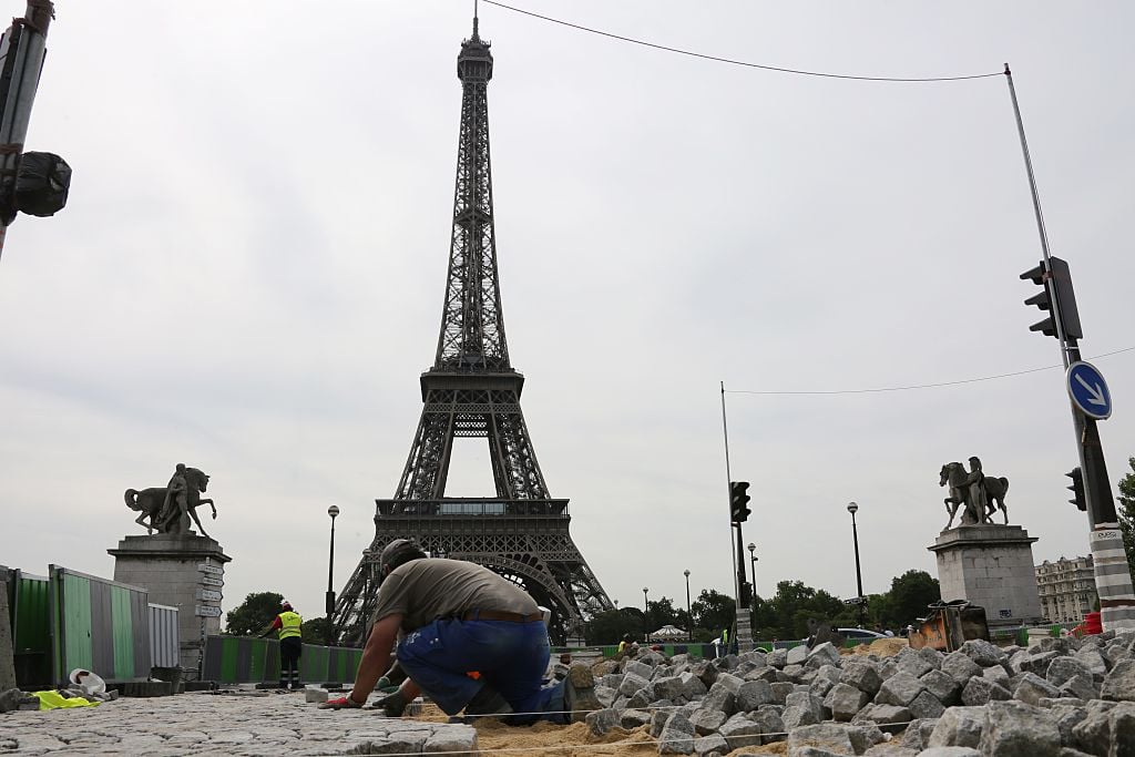 A worker lays historical cobblestone pavement on the road at Place de Varsovie by the Eiffel Tower in Paris on June 26, 2015. AFP PHOTO / LUDOVIC MARIN (Photo credit should read LUDOVIC MARIN/AFP/Getty Images)